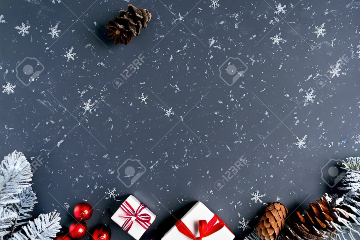 Christmas background with fir tree, Christmas present boxes, snowy fir branches, conifer cones,  gift on a dark background. Top view. Copy space. New Year. Decoration