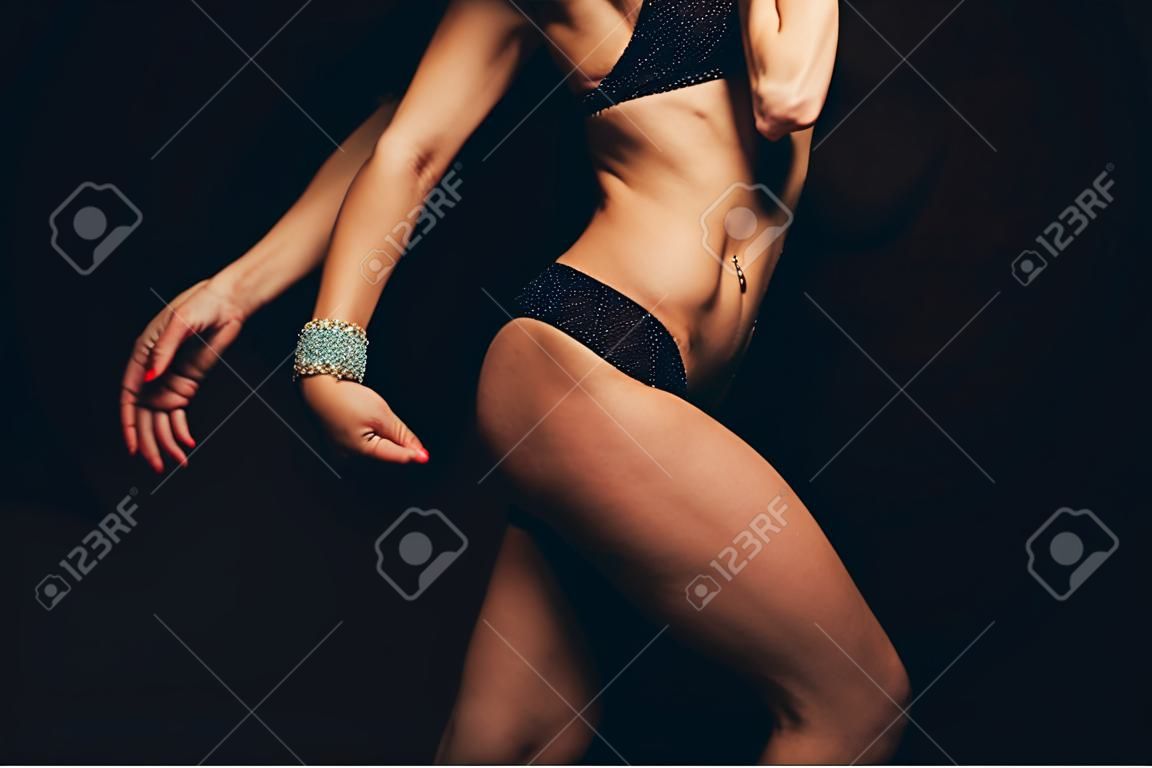 검정색 배경에 컬러 수영복을 입은 근육질 운동 젊은 여성. 적합. 근육질 몸매. 몸통. 복부 근육