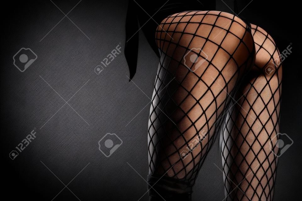 Le gambe femminili in calze a rete nere si chiudono