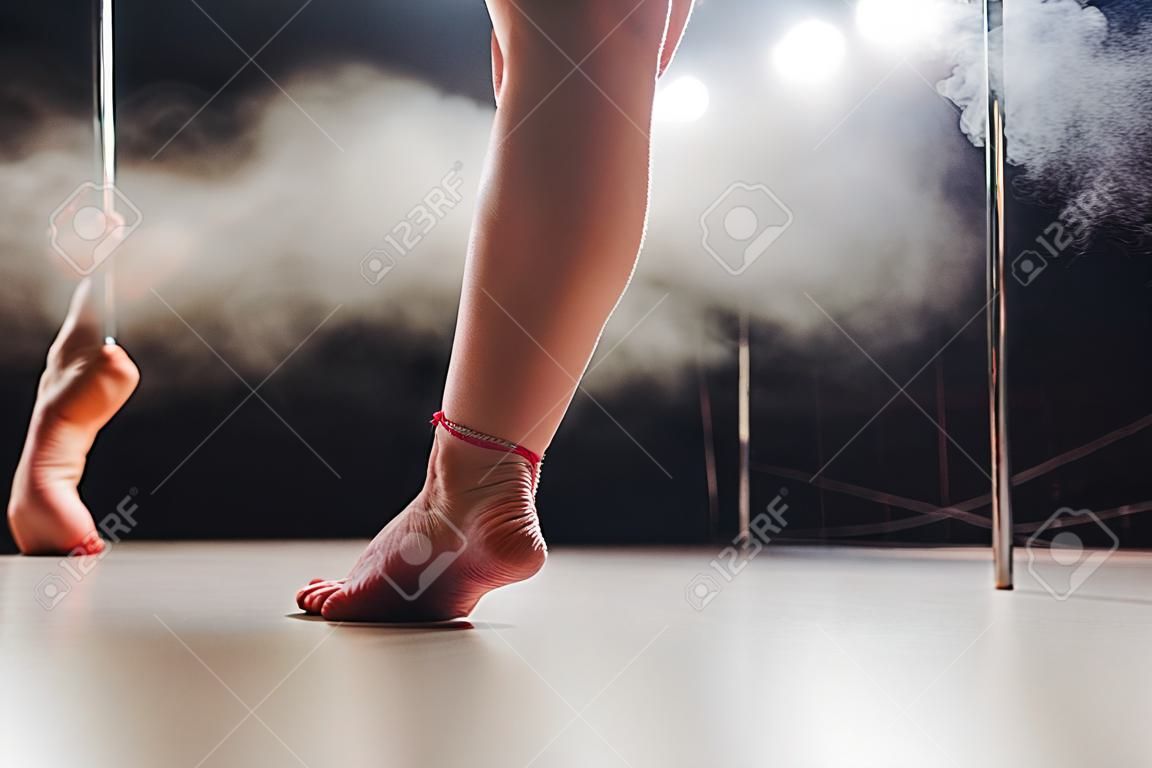 Red haired pole dance girl exercícios e poses no pílon na fumaça no fundo preto