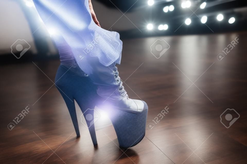 Frau zieht Schuhe an und tanzt auf Stangenstudio