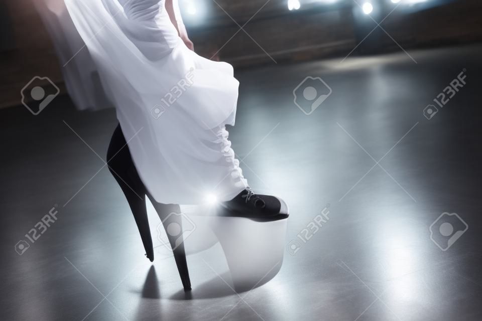 Frau zieht Schuhe an und tanzt auf Stangenstudio