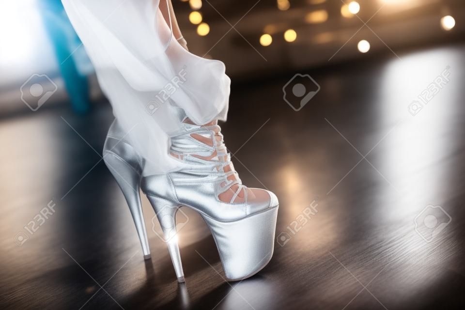Kobieta zakłada buty i tańczy na słupie studio