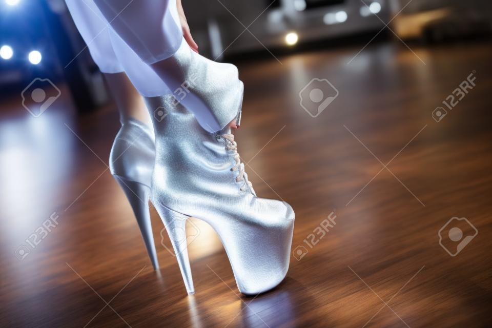 Kobieta zakłada buty i tańczy na słupie studio