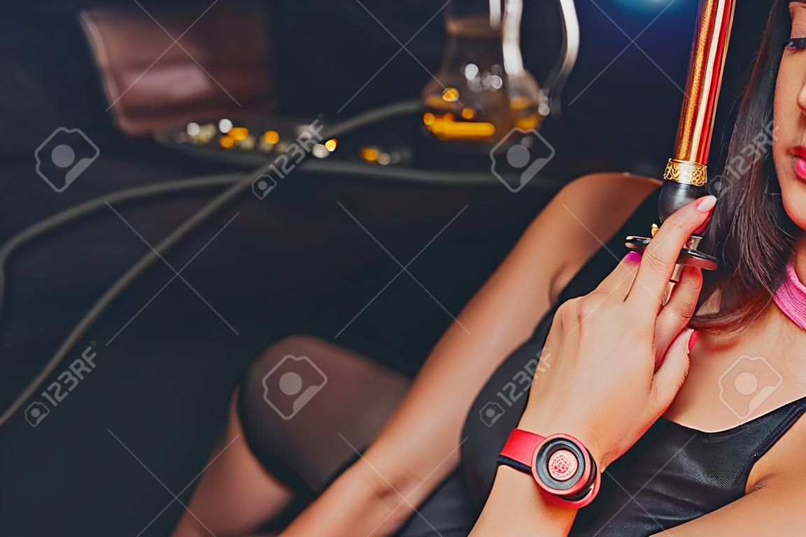 Girl is holding a hookah mouthpiece. Traditional oriental entertainment for adults is hookah smoking. Lifestyle and entertainment. Toning and post-processing.