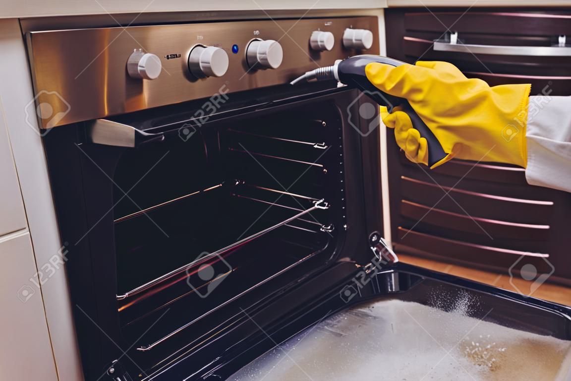 蒸気洗浄オーブンハウスクリーニング手のクローズアップ。