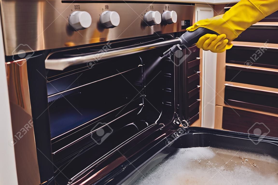 蒸気洗浄オーブンハウスクリーニング手のクローズアップ。