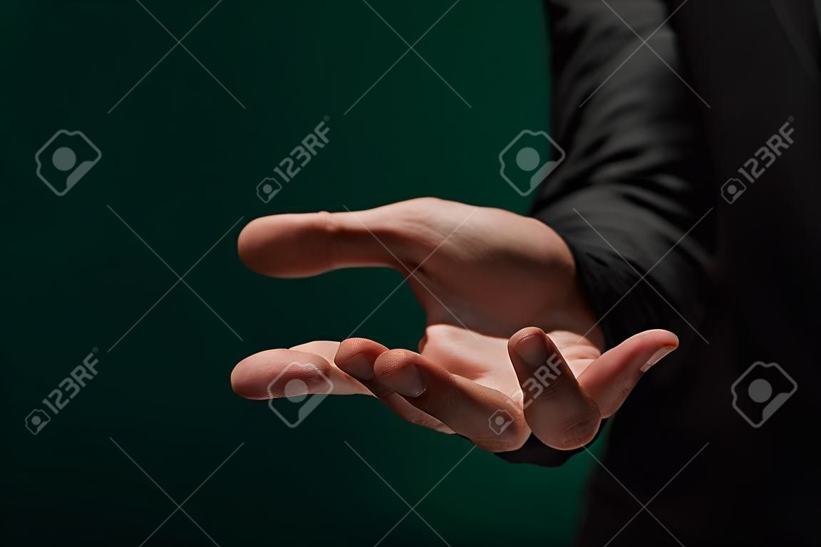 Vista laterale ravvicinata delle mani di un giovane non identificato con una camicia scura e una giacca che tiene un oggetto invisibile sul palmo. Il concetto di mani premurose. Concetto di pubblicità