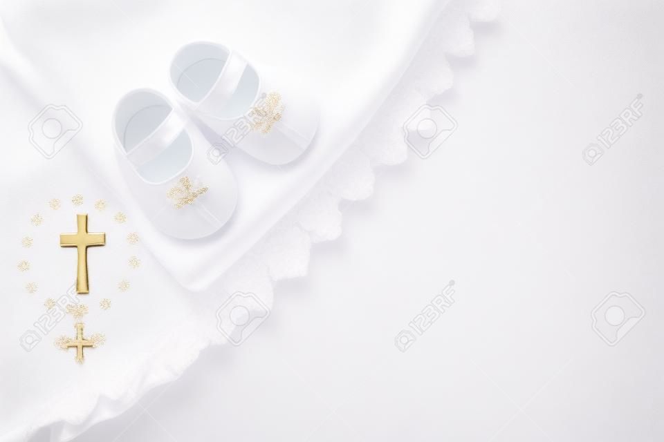 Christening background with baptism baby dress, shoes, and cross on pastel background