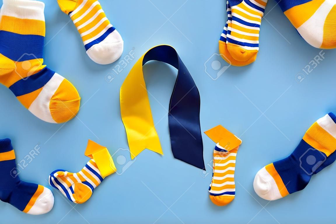 World Down syndrome day background. Down syndrome awareness concept. Socks and ribbon on blue background