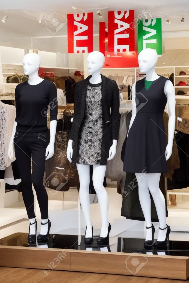 Mannequins displayed in a boutique with a sale signs hanging from the ceiling