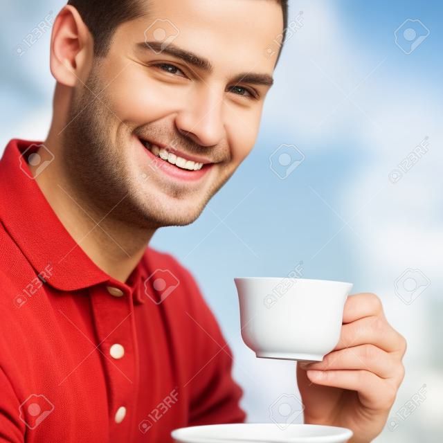 Retrato de joven feliz de café sonriendo hombre que bebía, al aire libre