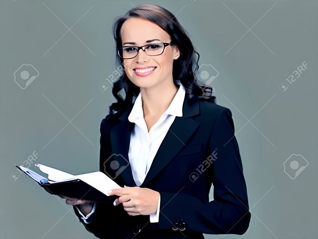 Cheerful smiling businesswoman in black suit with notepad or organizer, with blank copyspace area for slogan or text