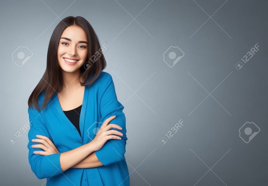 Porträt der jungen lächelnden Frau in der zufälligen intelligenten blauen Kleidung mit den gekreuzten Armen, mit copyspace Bereich für Text oder Slogan