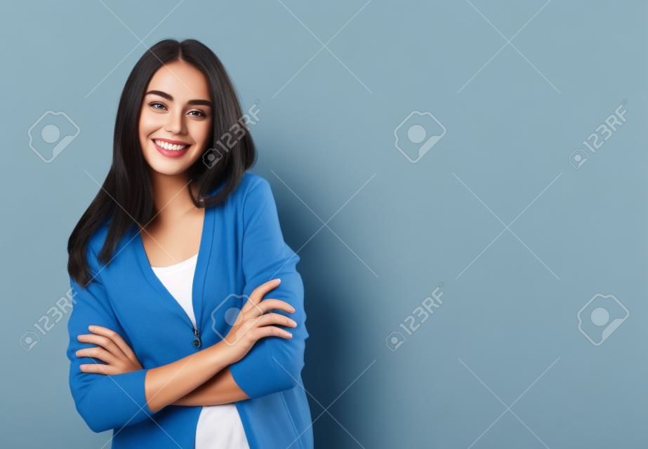 Porträt der jungen lächelnden Frau in der zufälligen intelligenten blauen Kleidung mit den gekreuzten Armen, mit copyspace Bereich für Text oder Slogan