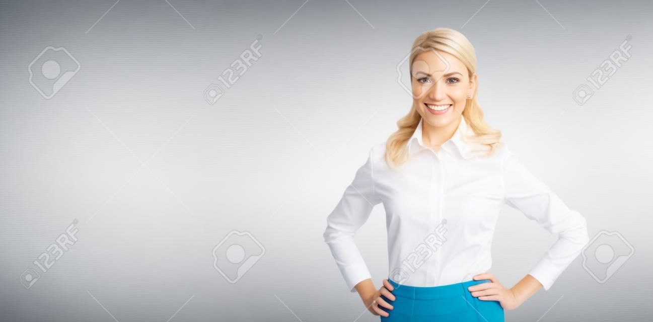 Portrait image of happy smiling businesswoman, with copy space area for text. Confident blond woman in white shirt standing in hands on hips pose, on blurred modern office background. Business concept