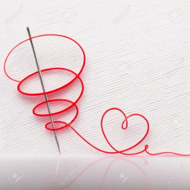 sewing needle with red thread on white background