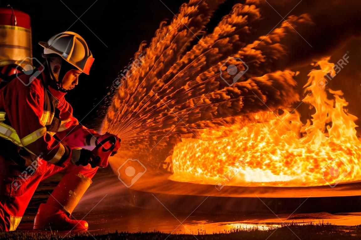 소방관들은 회전식 물안개식 소화기를 사용하여 기름에서 나오는 불길과 진압하여 불이 번지지 않도록 진압합니다. 소방관 및 산업 안전 개념입니다.