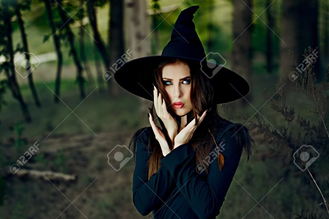woman witch in black hat in the forest posing fantasy
