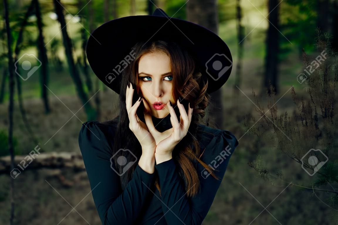 woman witch in black hat in the forest posing fantasy