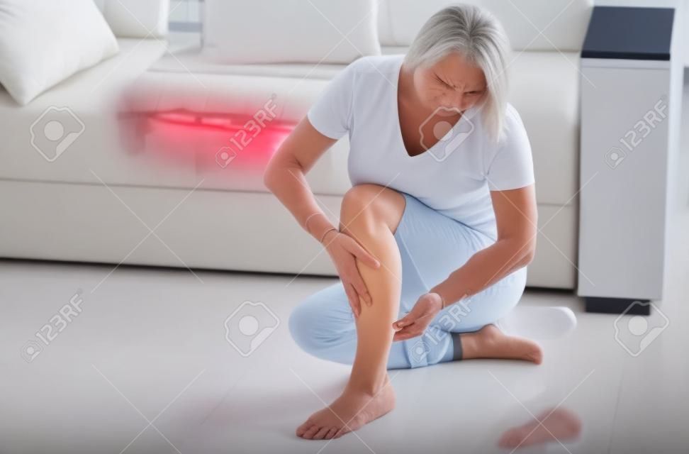 Kobieta w średnim wieku cierpiąca na ból nogi w domu, zbliżenie. Koncepcja obrażeń fizycznych.