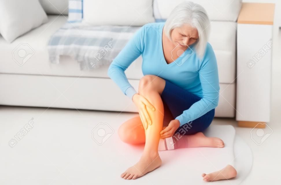 Kobieta w średnim wieku cierpiąca na ból nogi w domu, zbliżenie. Koncepcja obrażeń fizycznych.