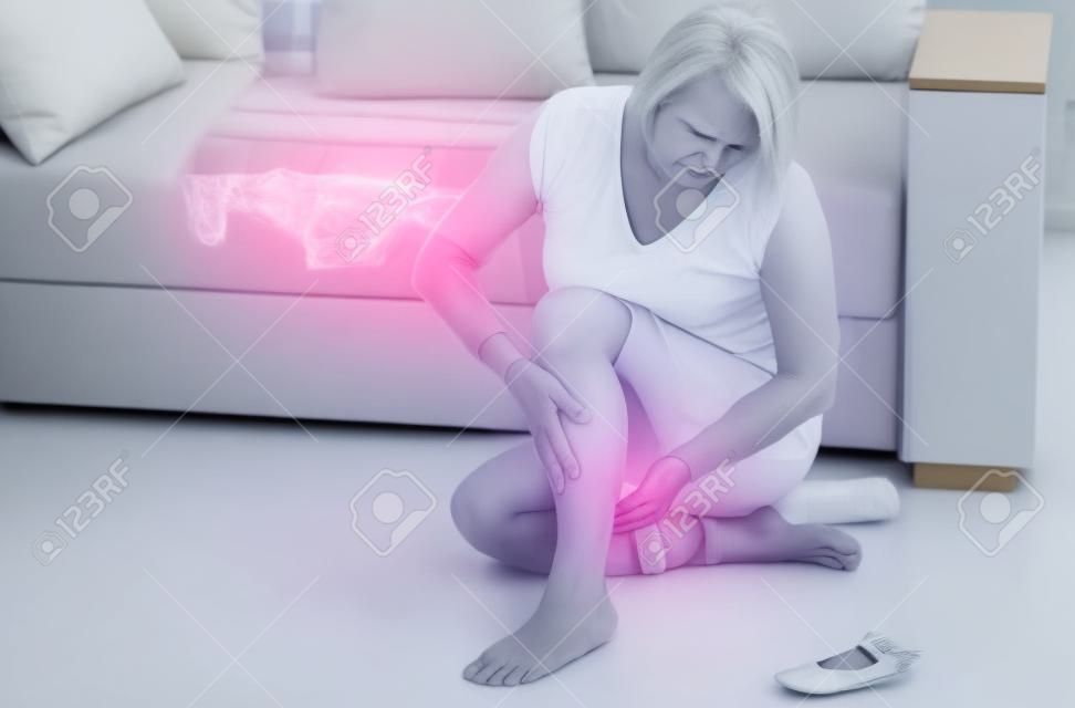 Middle-aged woman suffering from pain in leg at home, closeup. Physical injury concept.