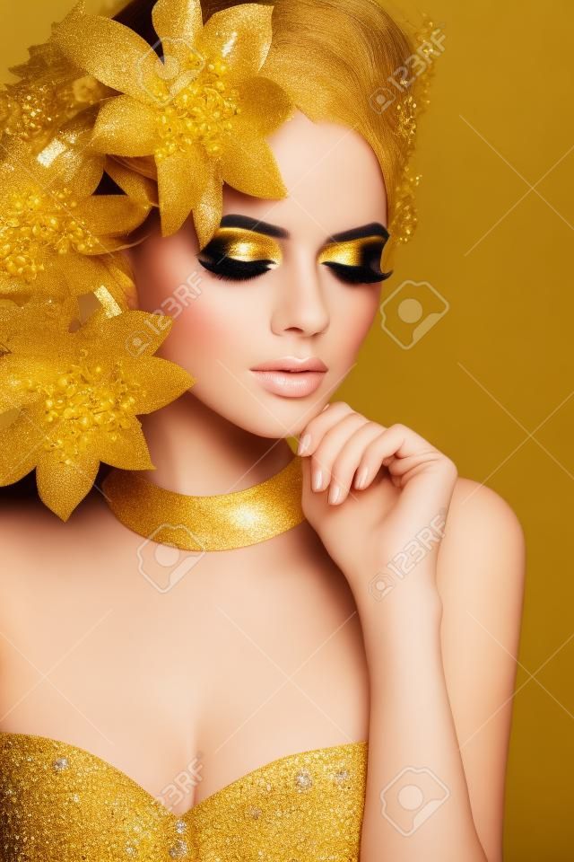 Glamour Makeup. Girl Face Close-up. Beauty Portrait Woman with golden flowers. Gold Jewelry. Hairstyle. Luxury photo