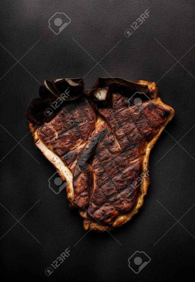 Roasted or grilled T-bone steak  on on dark rust metal background, top view, close up