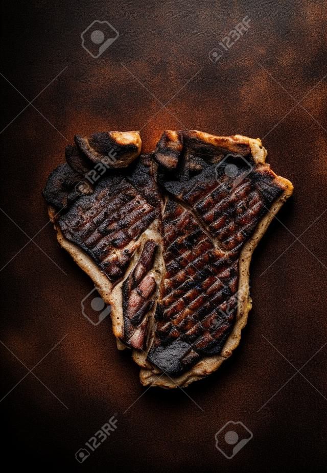 Arrosto o alla griglia T-bone steak su su sfondo metallo ruggine scuro, vista dall'alto, da vicino