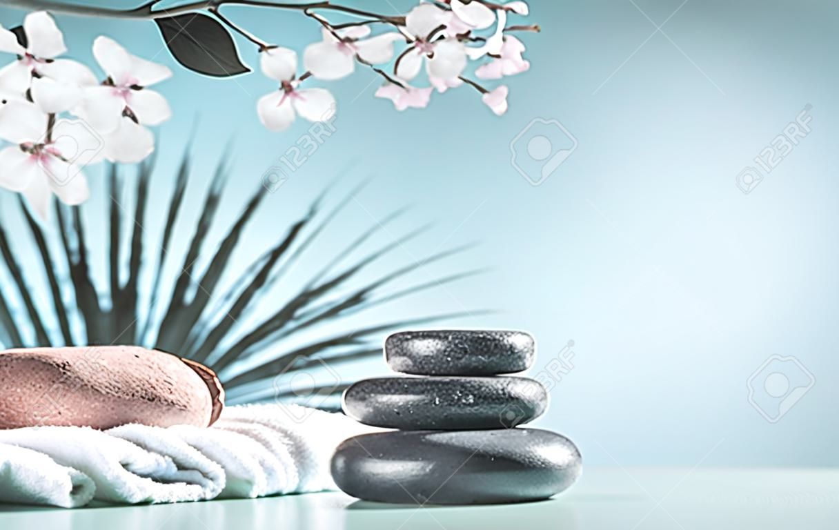 Zen stones with coconut and towels at light blue  with flowers.