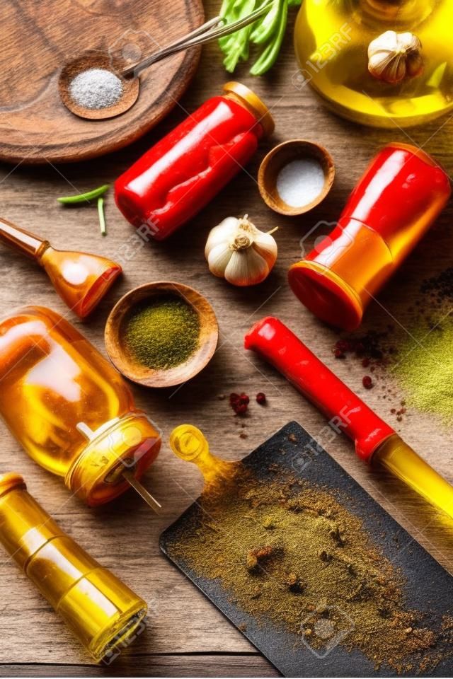 Leckere Kochzutaten für Lebensmittelaromen: Olivenöl, Gewürze, Salz und Pfeffer, Knoblauch, Chili in Dosen auf dunklem rustikalem Hintergrund. Ansicht von oben. Nahaufnahme