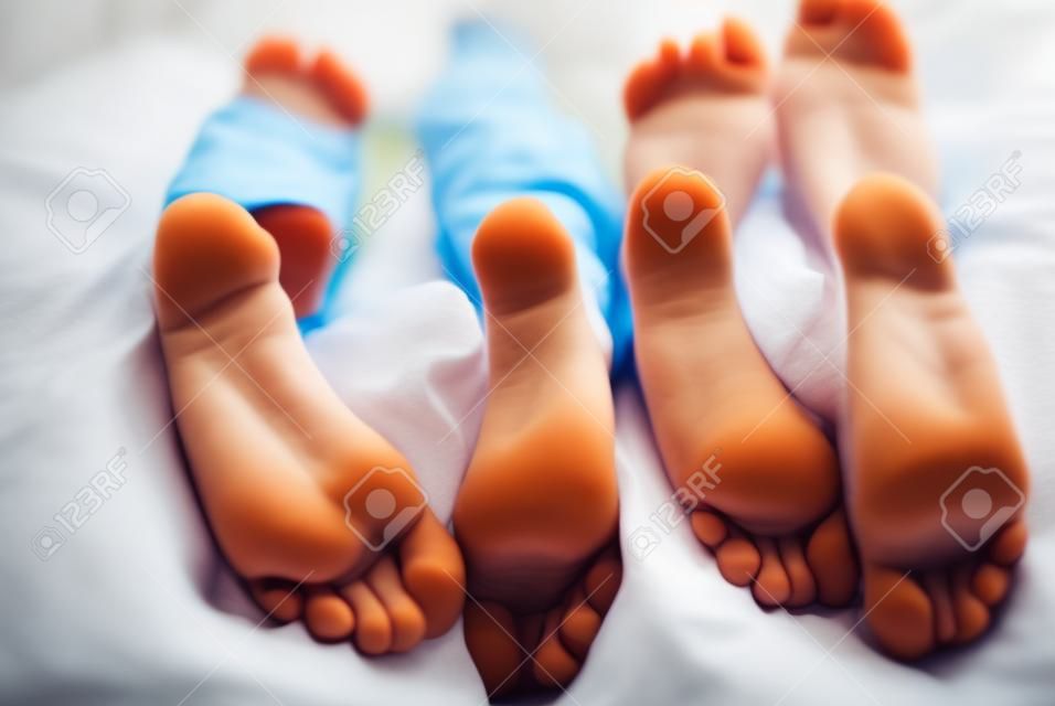 children lying in bed, kids feet close-up