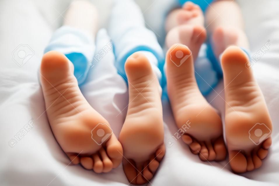 bambini sdraiati a letto, primo piano dei piedi dei bambini