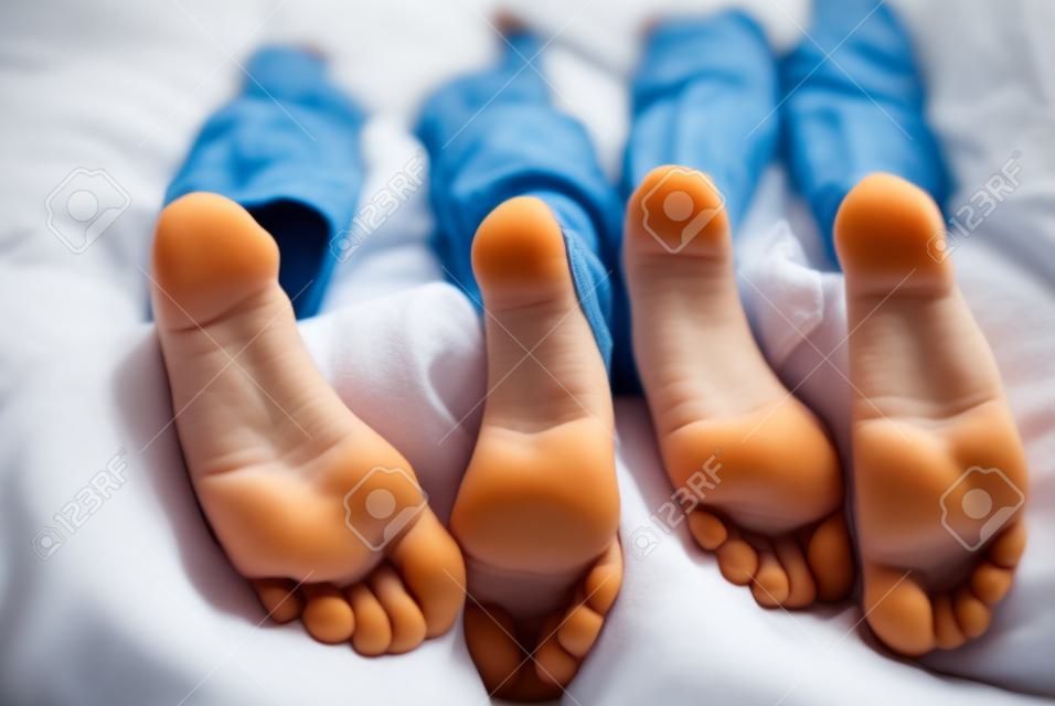 children lying in bed, kids feet close-up