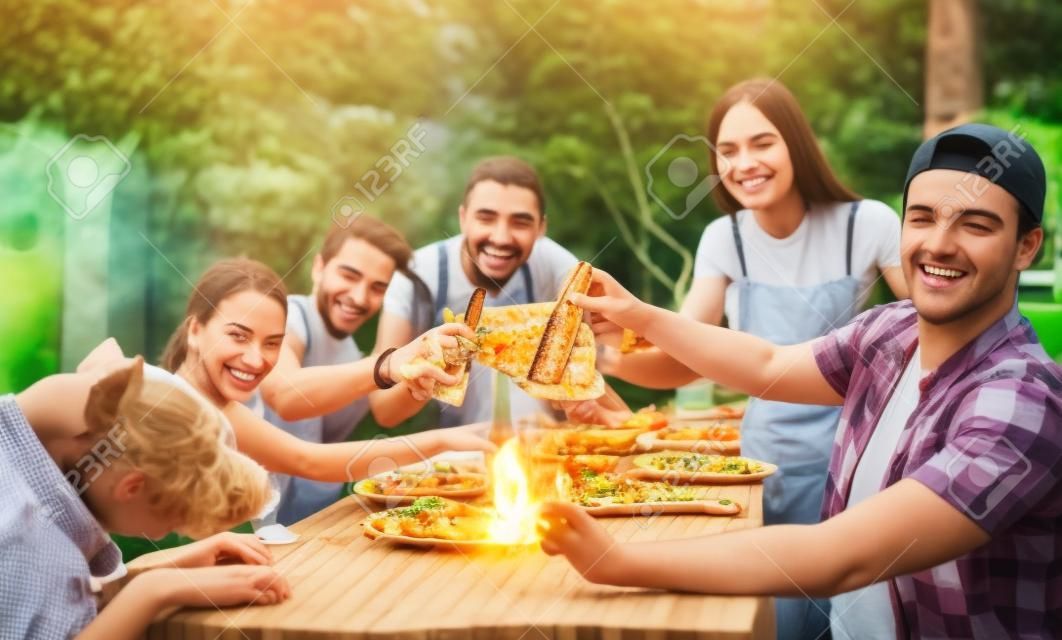 幸福觀與年輕人在家裡享受食物一起 - 快樂的朋友吃飯，敬酒，在花園裡燒烤組