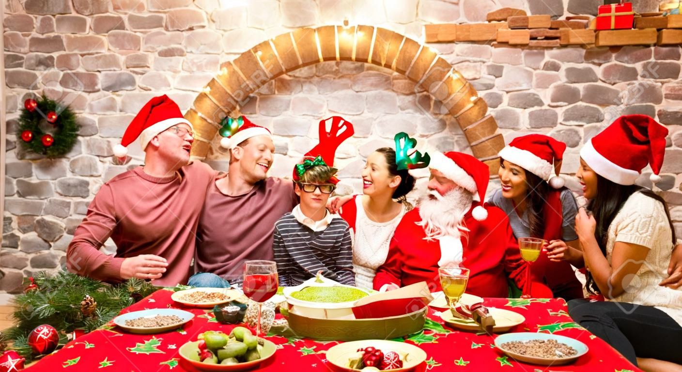 Foto de grupo de una familia de varias generaciones en ropa de sombreros de santa divirtiéndose en la fiesta de la casa de Navidad - Concepto de Navidad de vacaciones de invierno con padres e hijos comiendo juntos - Filtro rojo cálido y acogedor