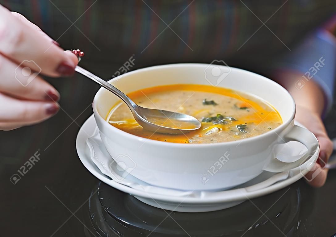Mano de mujer con la cuchara mientras come sopa en el restaurante