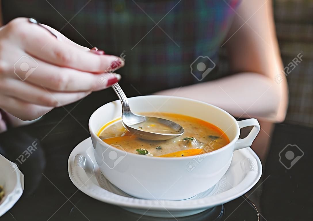 Mano de mujer con la cuchara mientras come sopa en el restaurante