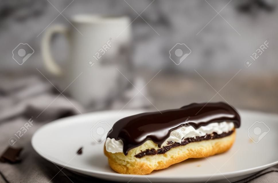 Eclair with chocolate topping on serving plate. Appetizing dessert and pastries.