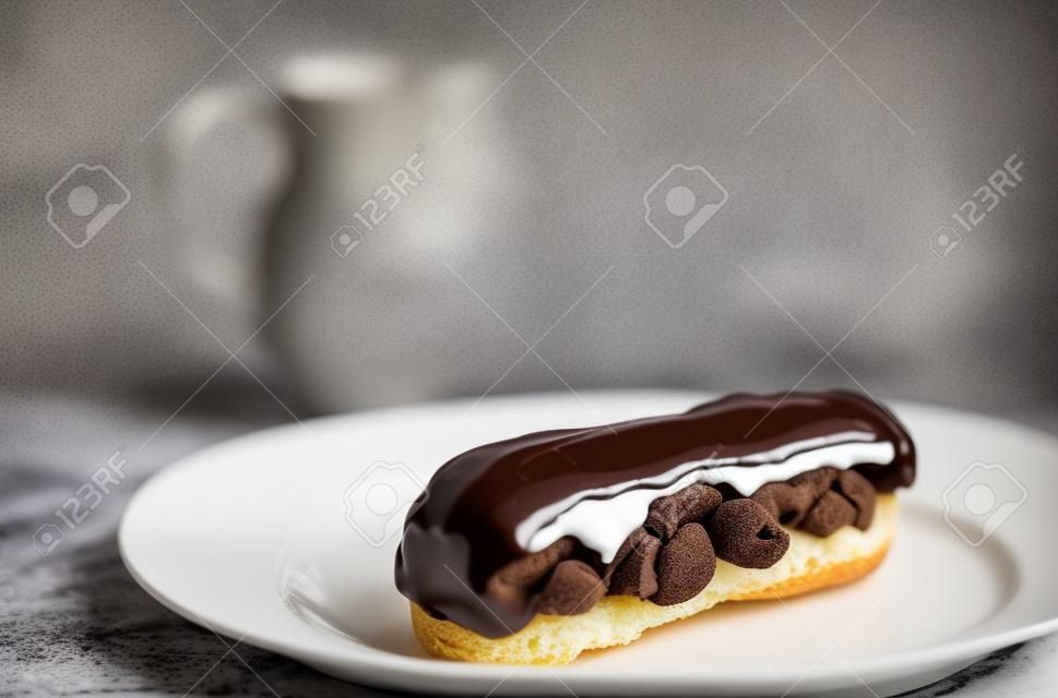 Eclair with chocolate topping on serving plate. Appetizing dessert and pastries.