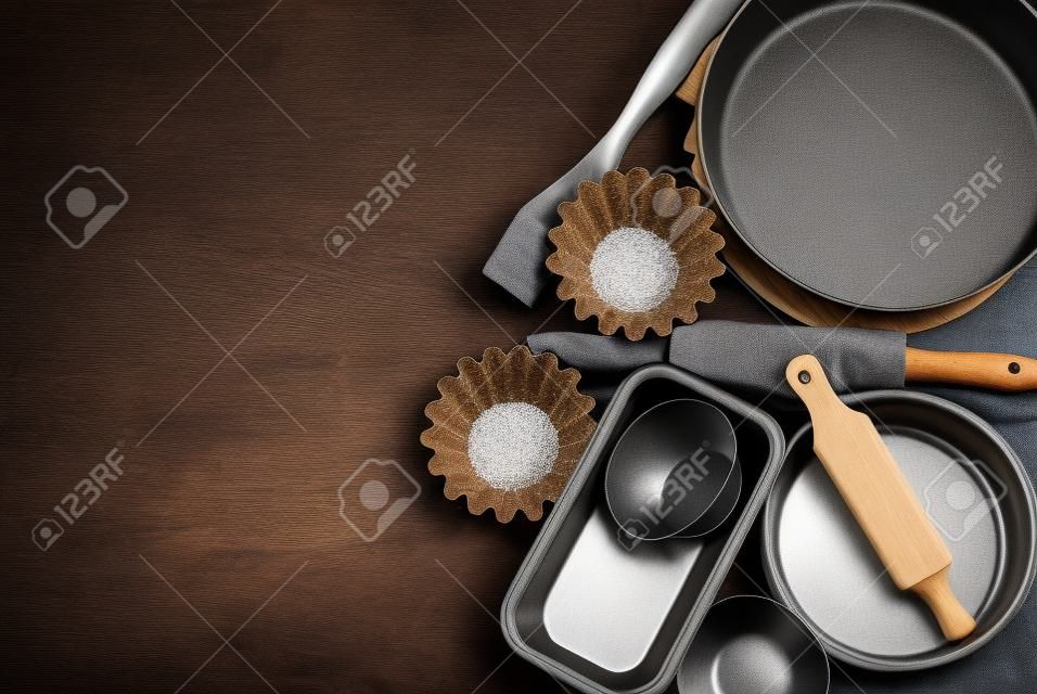 moules à gâteaux ronds et plats en métal, rouleau à pâtisserie en bois sur un fond en bois