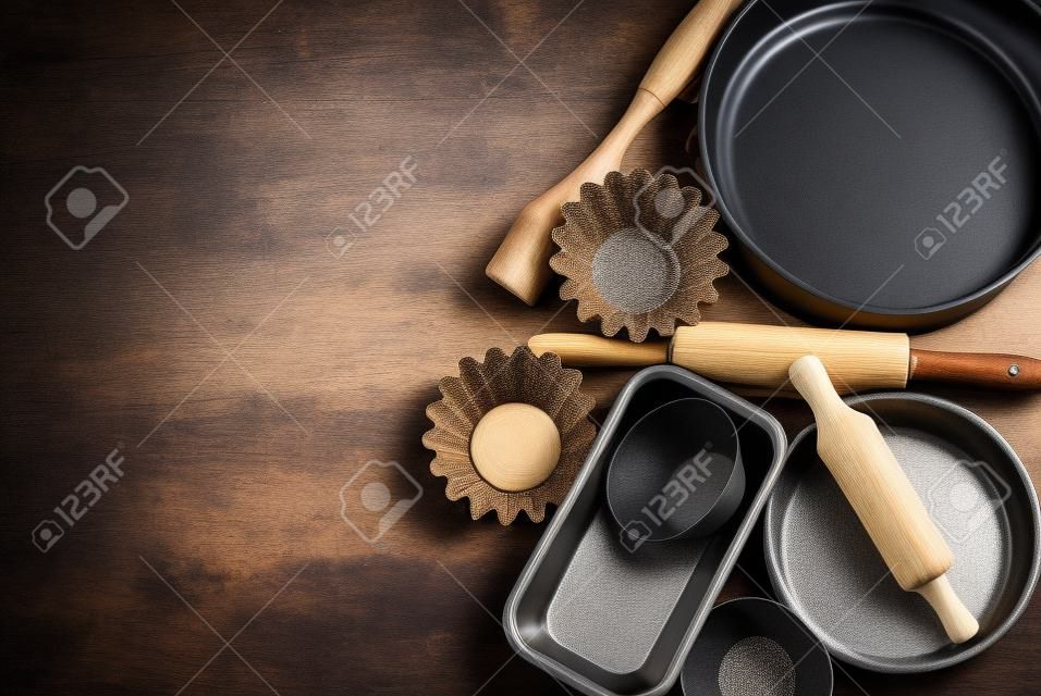 moules à gâteaux ronds et plats en métal, rouleau à pâtisserie en bois sur un fond en bois