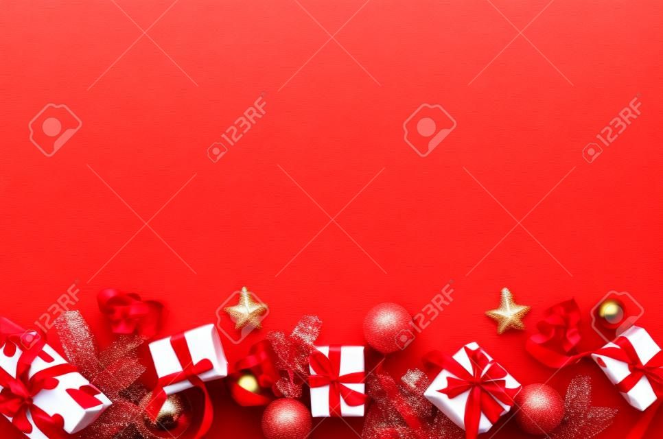 Concepto de decoración navideña. cajas de regalo envueltas en papel, adornos rojos y cinta sobre fondo rojo. endecha plana, vista superior. diseño de tarjeta de felicitación de año nuevo, plantilla de banner.