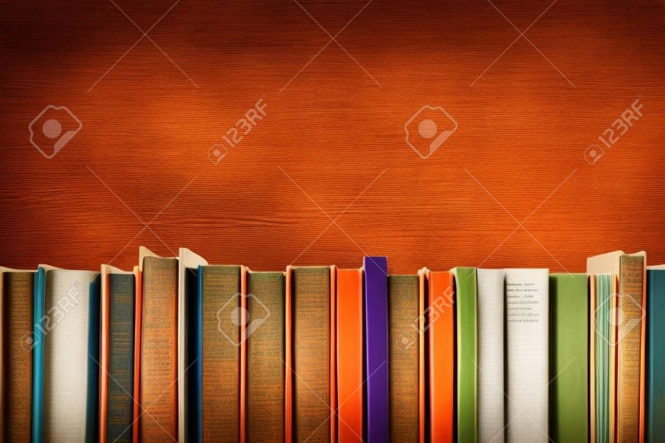 나무 데크 테이블과 오렌지 배경에 빈티지 오래 된 두꺼운 표지의 책 책, 일기와 다채로운 조성. 책은 스태킹. 학교로 돌아가다. 공간을 복사합니다. 교육 배경