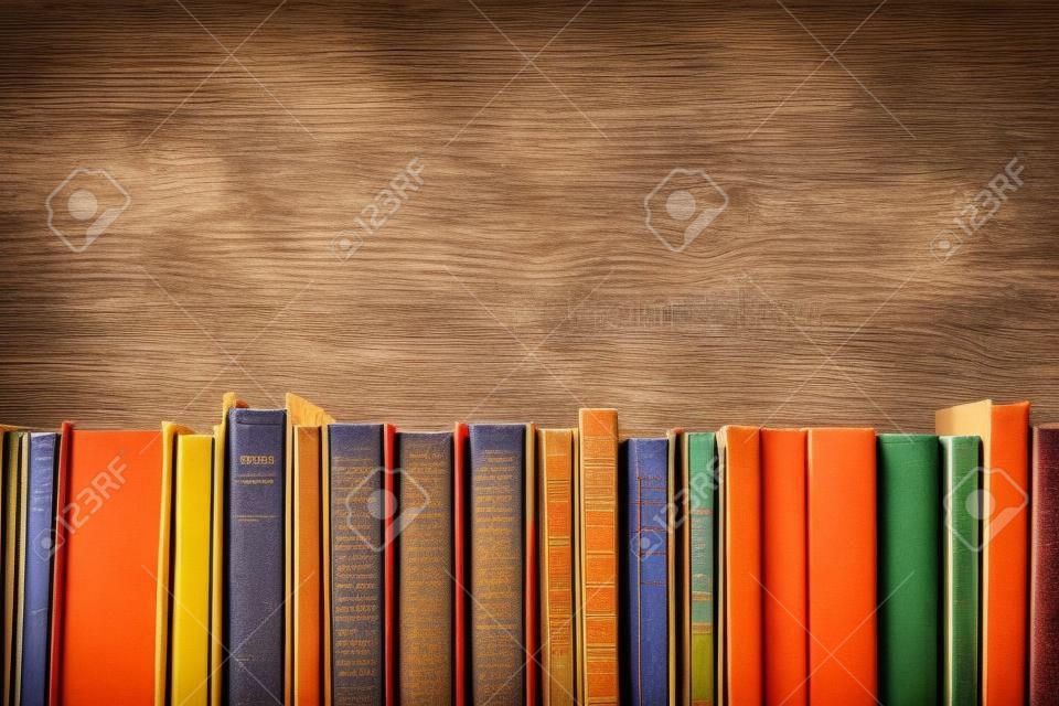 Colorful composizione con libri d'epoca antichi rilegati, diario sul tavolo ponte di legno e lo sfondo arancione. Libri accatastamento. Ritorno a scuola. Copiare lo spazio. Educazione di fondo