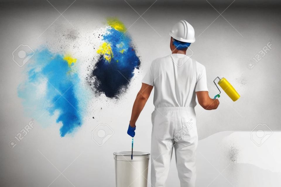 hombre pintor en el trabajo con un rodillo de pintura y cubo, el concepto de pintura mural