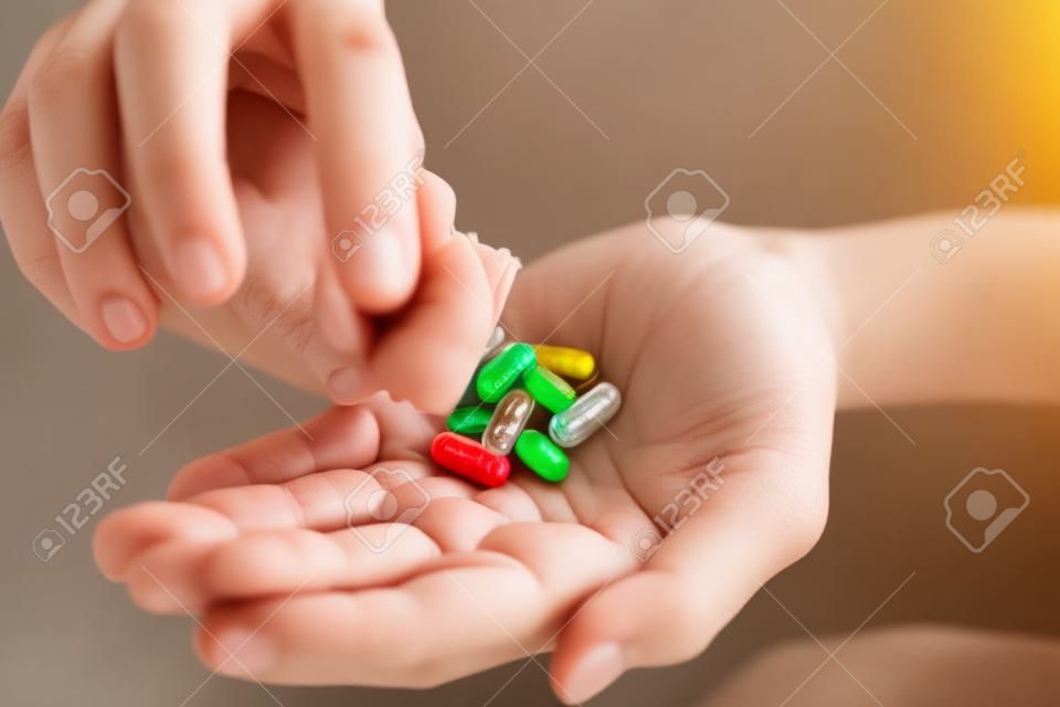 Close up woman hands holding vitamin pills, shaking them out of the bottle on the palm of her hand