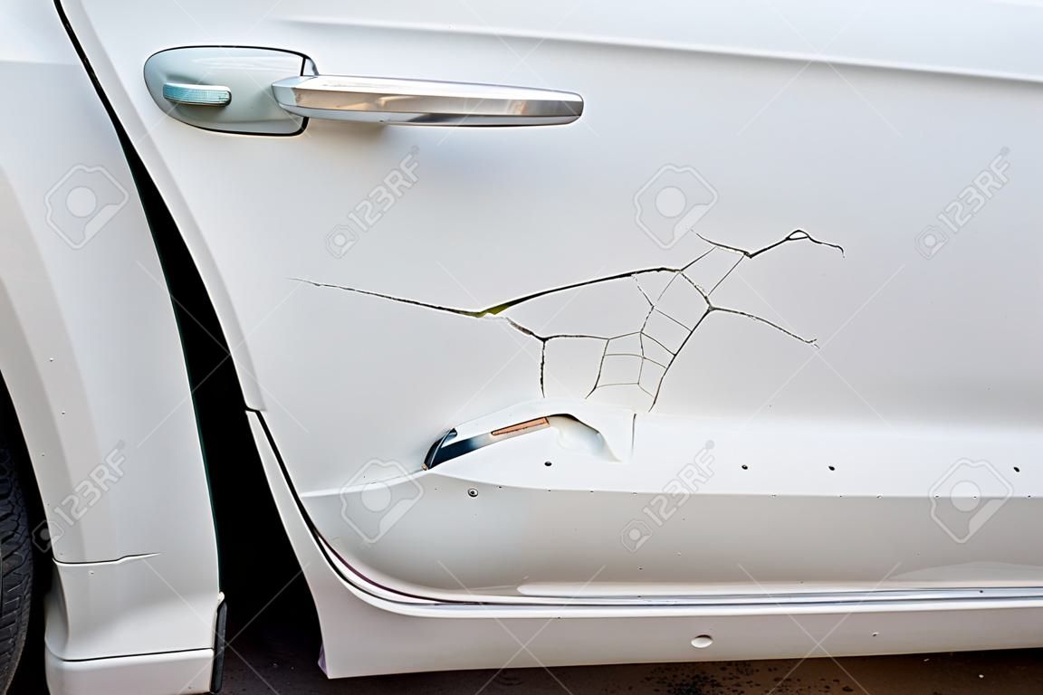 Abolladura, rasguño en la pintura blanca de la puerta del auto