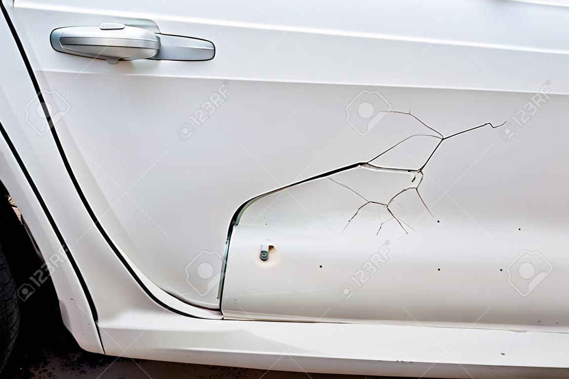 Wgniecenie na białym lakierze drzwi samochodu